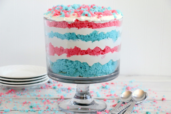 4 white dessert plates, 4 spoons and a trifle with layers of red white and blue.