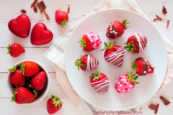 Valentines Day chocolate dipped strawberries. Above view table scene over a white wood background.