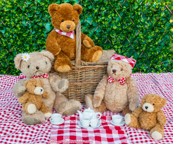Teddy Bear's picnic.  Five teddy bears enjoying a picnic in the garden with red and white gingham table cloth and white china teacups. 