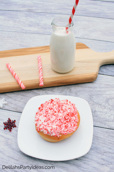 Donut on white plate with candy cane crushed up on top and a milk bottle with Milk and red and white straw