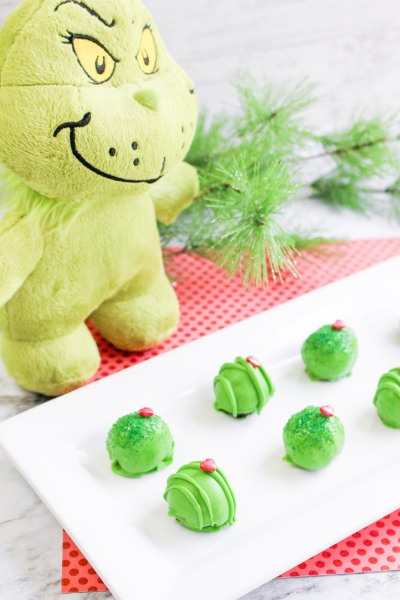 Soft Toy Grinch with a white plate on red tablecloth of Green Grinch Oreo Balls