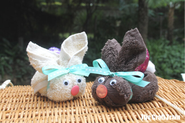 2 washcloths made into Easter Bunnies with Chocolate Easter Eggs on their backs