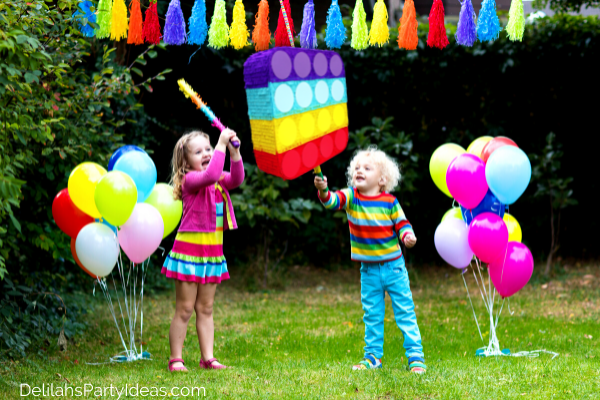 2 children at a Pop It Themed Party trying to hit the Pop It Pinata