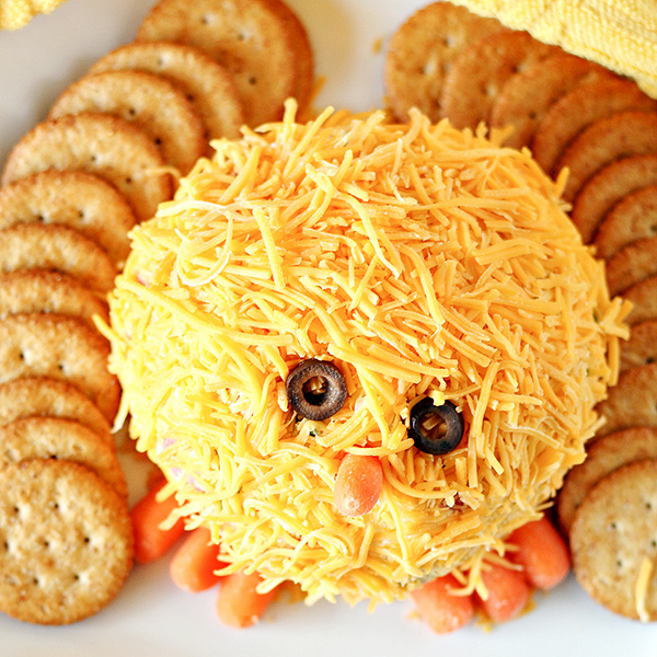 Cheese ball made into a little yellow chick with crackers on the side