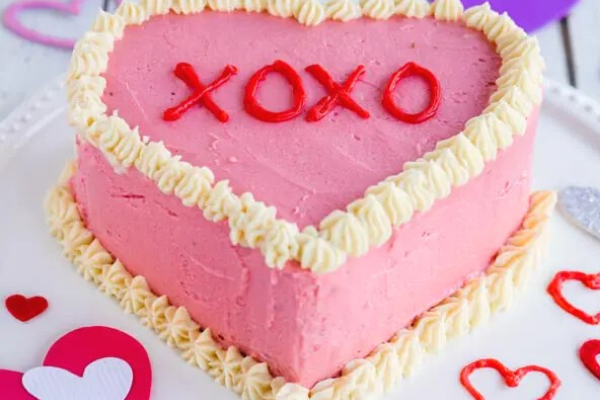 Heart shaped cake with pink icing and hugs and kisses on the top