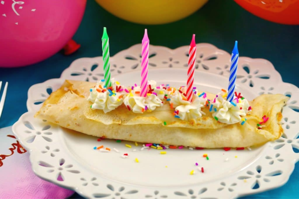 plate with birthday cake batter crepes with 4 candles