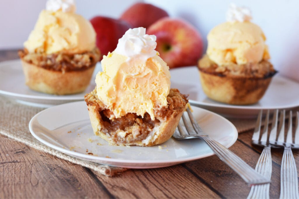 Mini apple pies on a plate with vanilla ice cream and whipped cream