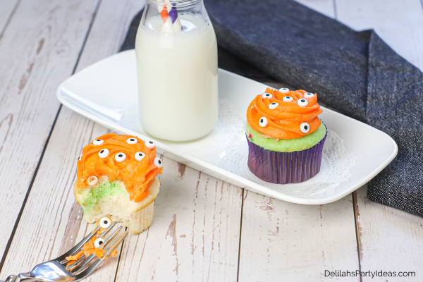 2 spooky eye cupcakes on a white plate with a glass of milk