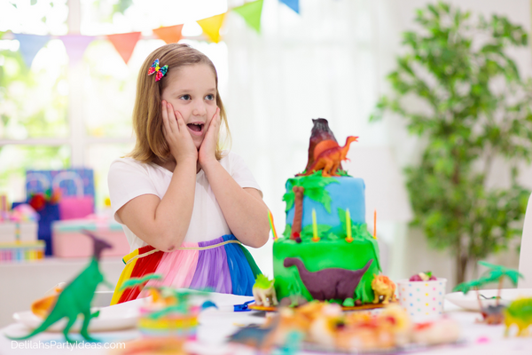 Girl Dinosaur Party Ideas, young girl with a dinosaur birthday cake