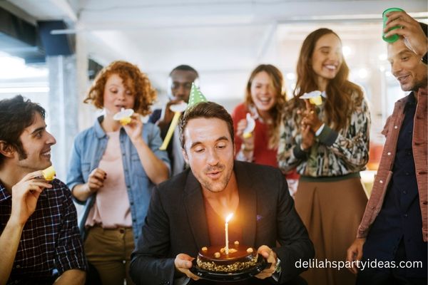 Male blowing out candle on birthday cake at work