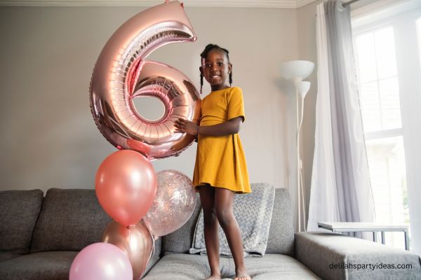 Girl holding number 6 balloon