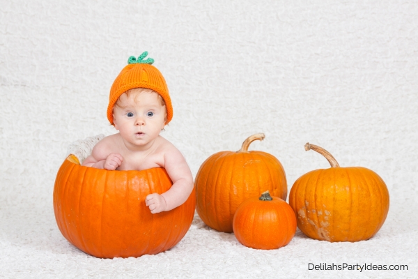 Baby inside pumpkin, surrounded by pumpkins