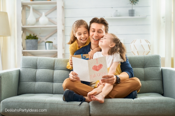 Father holding card with his 2 daughters