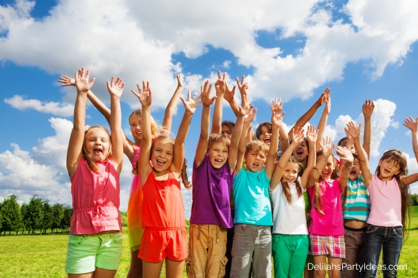 Group of happy kids outdoors with their arms raised 