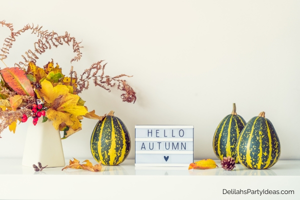 Bouquet of leaves on vase, decorative pumpkins, letterboard with "hello autumn"