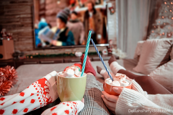 2 persons holding mugs of hot cocoa, watching a Christmas movie