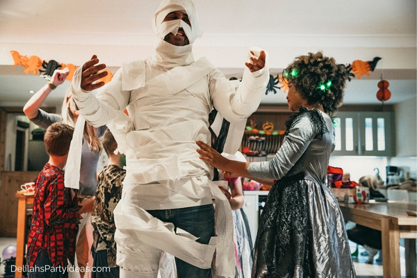 girl rolling toilet paper into her dad to look like a mummy