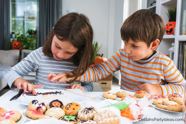 a girl and boy designing halloween cookies