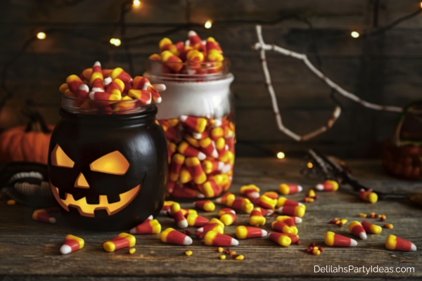 jar full of candy corns, pumpkin shaped jar with candy corns, candy corns scattered on table