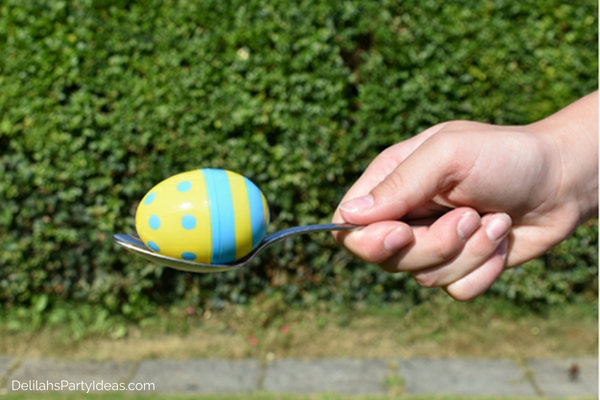 A hand holding a spoon with an Easter egg on it