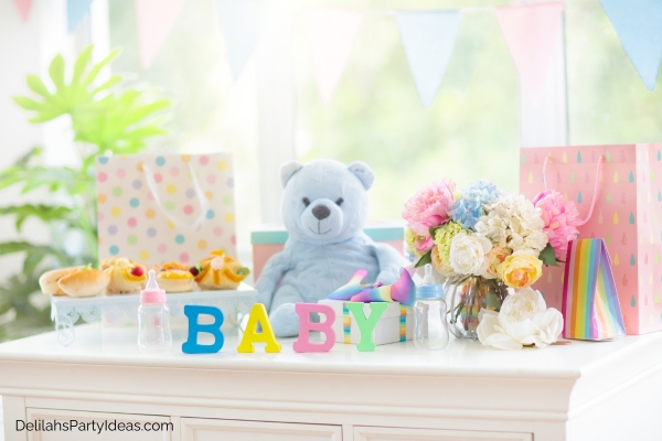 Baby shower decor of teddy bear, flowers, pastel colored paper bags, finger foods