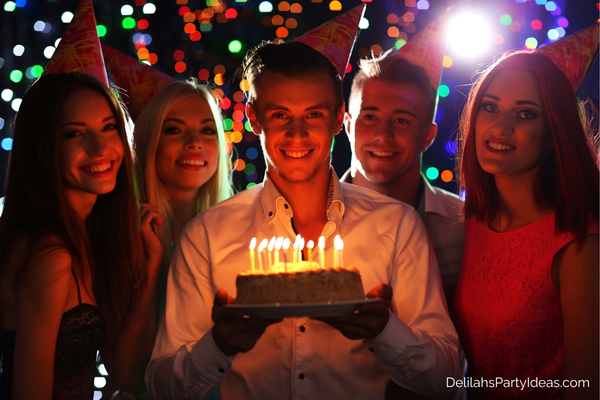 man with birthday cake surrounded by friends