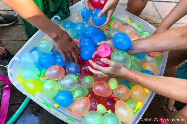 hands grabbing water balloons from a bucket