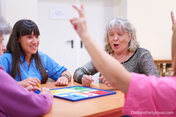 elderly women playing a board game with caregivers