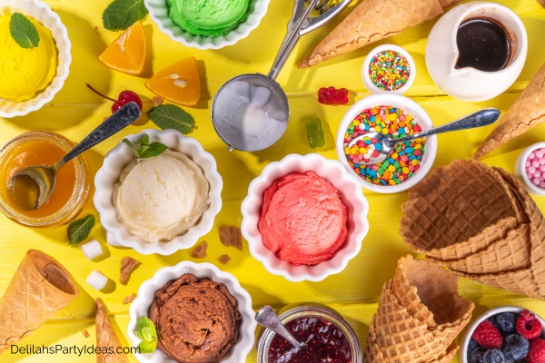 various bowls of ice cream with assorted bowls of topping, sugar cones, sauces