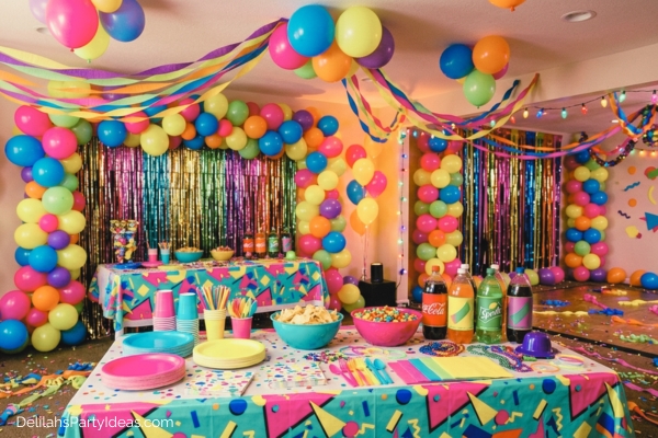 80s party decorations of bright colorful balloons, streamers, table cloth, plates and cups