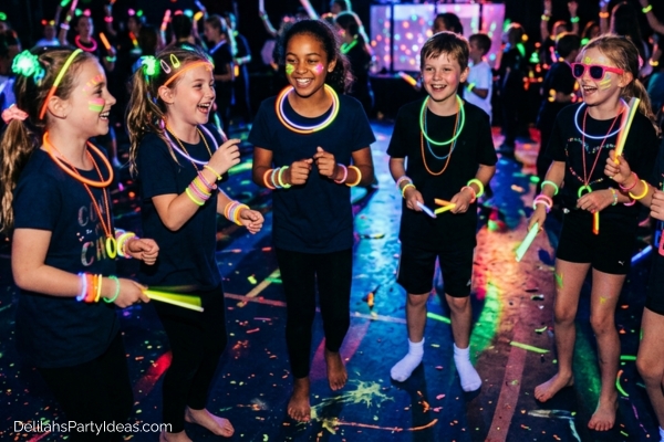 kids wearing glow in the dark necklaces and bracelets, holding glow sticks, in a glow in the dark party