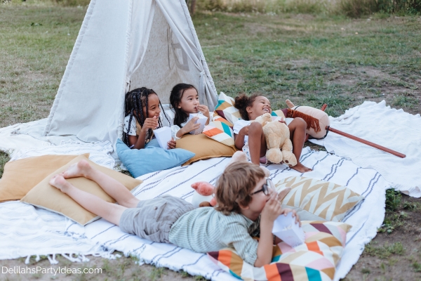 little kids having watching a movie in the backyard 
