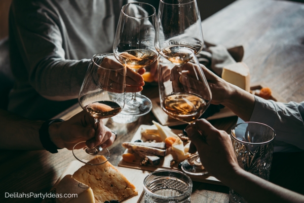 group of friends clicking their wine glasses at a wine and cheese party