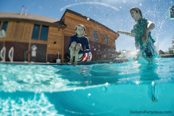 2 kids doing a cannon ball in a pool
